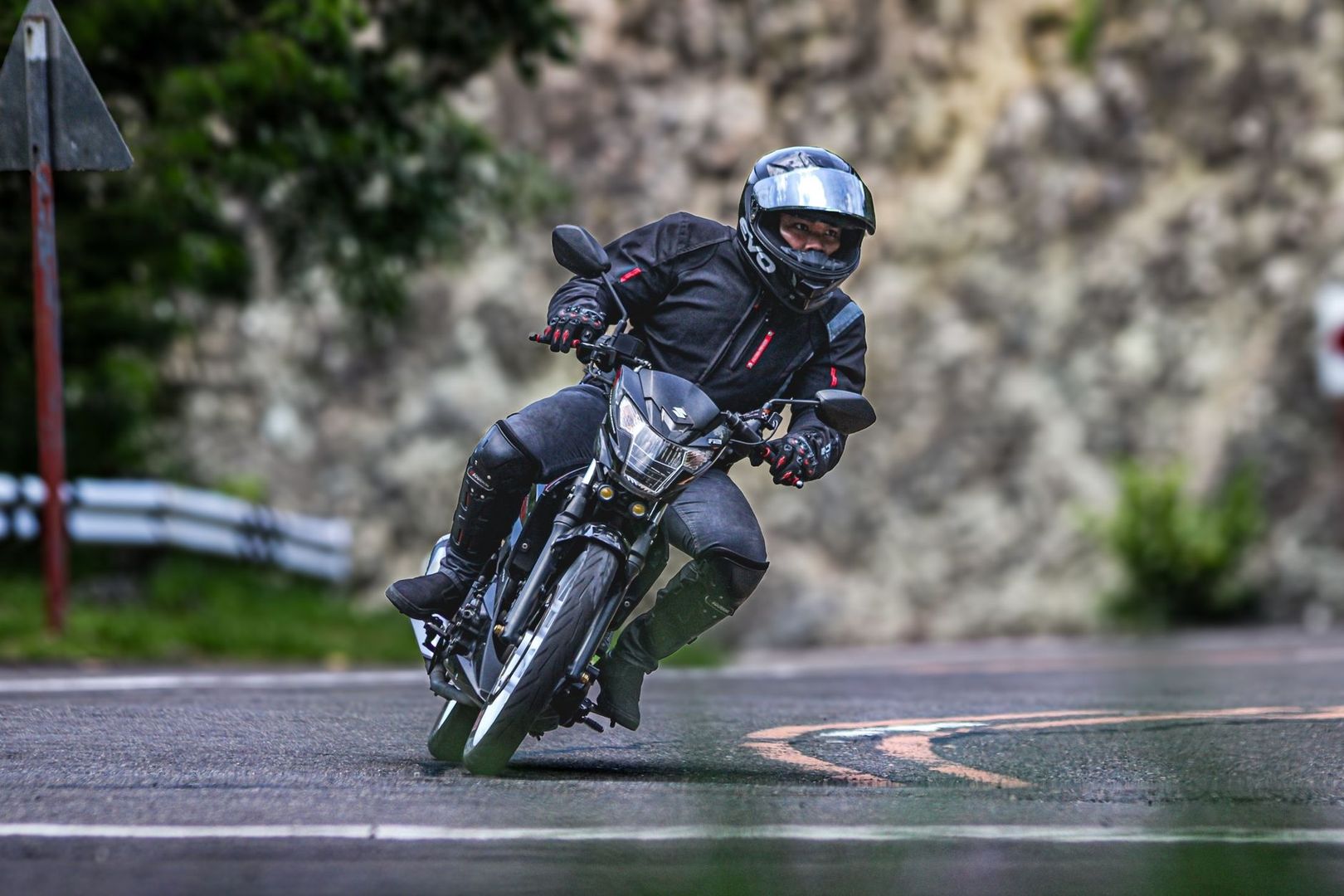 Motard équipé prenant un virage incliné sur une route humide